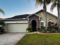 Charming single-story home with a stone entryway, lush landscaping, and a paved driveway at 10942 High Bush Ct, Orlando, FL 32825