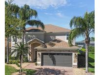 Beautiful two-story home with a well-manicured lawn and mature palm trees creating a tropical ambiance at 13643 Budworth Cir, Orlando, FL 32832