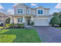 Charming two-story home boasts a brick driveway, manicured lawn, and inviting curb appeal at 1702 Reflection Ln, St Cloud, FL 34771