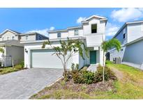 Charming two-story home featuring a teal front door, manicured landscaping, and a gray brick driveway at 3320 Lilac Way, Davenport, FL 33897