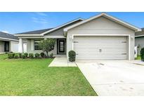 Charming single-Gathering home featuring a well-manicured lawn, two-car garage, and inviting front entrance at 405 Bandon Dunes Loop, Davenport, FL 33837
