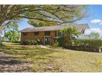 Charming brick two-story home with a lush front yard and mature trees, offering a serene and inviting curb appeal at 13224 Casper Ln, Clermont, FL 34711