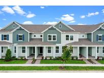 Charming exterior view of townhomes featuring a manicured lawn, and a covered porch with classic white pillars at 13809 Luna Harvest Ave, Winter Garden, FL 34787