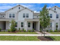 Charming townhome with light gray exterior, landscaped front yard, and covered entryway at 13809 Luna Harvest Ave, Winter Garden, FL 34787
