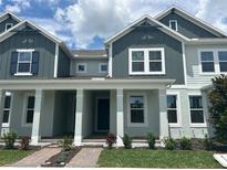 Charming two-story townhome featuring a covered porch, lush landscaping, and a welcoming entrance at 13809 Luna Harvest Ave, Winter Garden, FL 34787