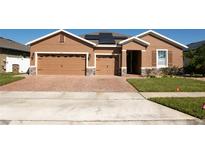 Stunning single-story home boasting a 3-car garage, solar panels, and a beautifully paved driveway and walkway at 1855 Partin Terrace Rd, Kissimmee, FL 34744