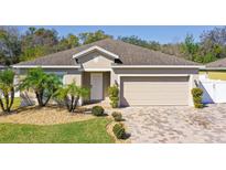Charming single-story home featuring a well-maintained lawn, paver driveway, and an attached two-car garage at 188 Whispering Pines Way, Davenport, FL 33837