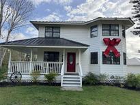 Charming two-story farmhouse exterior with a welcoming front porch and a vibrant red front door at 1955 Mustang Ct, St Cloud, FL 34771