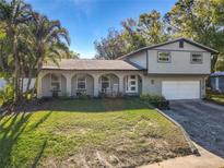 Charming home featuring a well-manicured lawn, palm trees, white rocking chairs, and a two-car garage at 210 Carriage Hill Dr, Casselberry, FL 32707