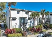Two-story condo featuring tropical landscaping, black shutters, and a staircase leading to the front door at 4215 S Semoran Blvd # 2, Orlando, FL 32822