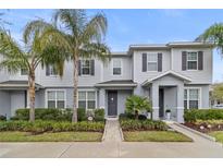 Inviting townhome featuring a manicured lawn, gray siding, and dark shutters at 6067 Blue Lily Way, Winter Garden, FL 34787