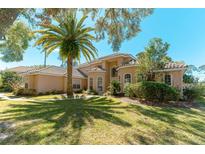 Inviting Mediterranean home with a tile roof, stucco facade, and mature landscaping including a beautiful palm tree at 9833 Camberley Cir, Orlando, FL 32836