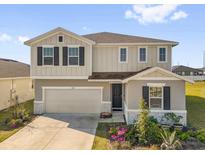 Charming two-story home with a two-car garage, well-maintained lawn, and complemented by colorful flowers at 1209 Mattie Pointe Blvd, Auburndale, FL 33823