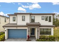 Modern two-story home boasts a blue garage door, stone accents, and lush landscaping at 1242 Butterfly Orchid Rd, Davenport, FL 33837