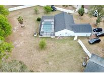 Aerial view of the screened-in pool and backyard of a single-Gathering home with mature trees and landscaping at 15438 Petrus Ln, Clermont, FL 34714