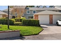 Well-maintained home exterior with green lawn, mature landscaping, and brick accented garage at 610 Chestnut Oak Cir # 114, Altamonte Springs, FL 32701