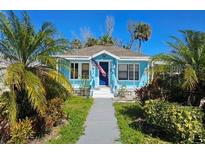 Charming turquoise home with an American flag, lush landscaping, and a welcoming pathway at 723 Dougherty St, New Smyrna Beach, FL 32168