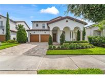 Charming home with manicured front yard, arched entry, and a two-car garage and brick paved driveway at 8025 Topsail Pl, Winter Garden, FL 34787