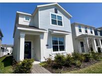 Charming two-story home featuring a blue accent wall, manicured landscaping, and a welcoming covered entryway at 9787 Introduction Way, Orlando, FL 32832
