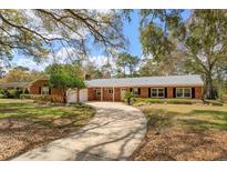 Charming one-story brick home with a lush front yard, long driveway and mature shade trees at 1322 Ensenada Dr, Orlando, FL 32825