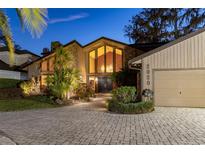 Stunning home exterior featuring stone accents, large windows, lush landscaping, and a paver driveway at 2020 Venetian Way, Winter Park, FL 32789