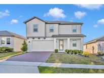 Beautiful two-story home featuring light grey paint, manicured lawn and a brick paver driveway at 2291 Raven Ridge Rd, Minneola, FL 34715