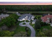 Breathtaking aerial view of an estate home with lush landscaping, water features, and a circular driveway at dusk at 2453 Alaqua Dr, Longwood, FL 32779