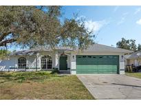 Single-story home with a two-car garage, arched windows, and a well-maintained front lawn at 3275 Deer Lick Ct, Kissimmee, FL 34746