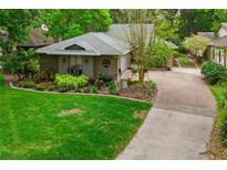 Aerial view of charming home featuring lush green lawn, mature trees and a paved driveway at 106 Waterwood Dr, Yalaha, FL 34797