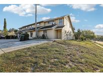 Inviting exterior of tan townhome featuring a well-maintained lawn and neutral color palette at 1239 Woodman Way, Orlando, FL 32818