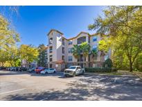 Mediterranean-style building with four stories, a tile roof, palm trees and ample parking space under a blue sky at 1301 Tuscan Ter # 9405, Davenport, FL 33896