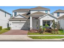 Charming two-story home with a brick driveway, manicured lawn and gray exterior at 14399 Wabasso Loop, Winter Garden, FL 34787