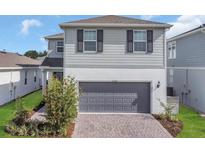 Charming two-story home with a gray garage and brick-paved driveway at 17398 Saw Palmetto Ave, Clermont, FL 34714