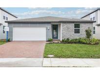 Beautiful single-Gathering home featuring stone and modern gray siding, landscaped yard, and a brick driveway at 2929 Wild Olive Dr, St Cloud, FL 34772