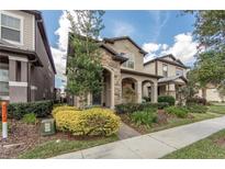 Charming two-story home featuring a stone facade, well-manicured landscaping, and inviting front porch at 7112 Enchanted Lake Dr, Winter Garden, FL 34787