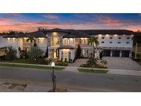Stunning exterior view of a luxury home with manicured landscaping and a paver driveway at sunset at 1148 Grand Traverse Pkwy, Reunion, FL 34747