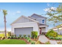 Charming two-story home with gray siding, a landscaped yard, and a welcoming red front door at 1224 Teal Creek Dr, St Cloud, FL 34771