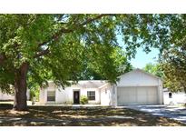 Cozy single story house with a two car garage surrounded by lush green trees at 12312 Woodglen Cir, Clermont, FL 34711
