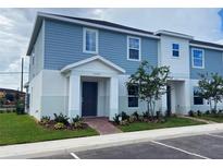 Charming two-story townhome featuring a blue exterior with well manicured landscaping at 1234 Sand Torch Cir, Davenport, FL 33837