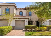 Charming two-story home with a brick-paved driveway, lush landscaping, and a mix of stone and stucco finishes at 14023 Tarvin St, Orlando, FL 32832