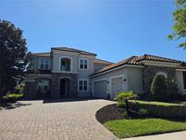 Stunning two-story home featuring a beautiful terracotta roof, stone accents, and a paver driveway at 14172 Hutchinson St, Winter Garden, FL 34787