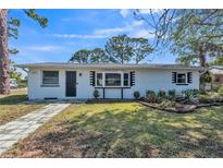 Charming one-story white brick home with well-maintained landscaping and a walkway leading to the front door at 1607 India Palm Dr, Edgewater, FL 32132