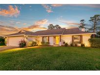 Attractive brick home with neat landscaping, features an attached garage and a cozy, well-lit entryway at twilight at 425 N Pine Meadow Dr, Debary, FL 32713