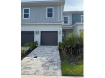 Charming home featuring a two-car garage, gray brick driveway, and well-manicured landscaping at 7810 Spectrum Dr, Kissimmee, FL 34747