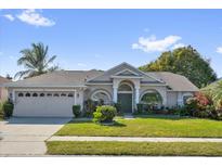 Charming one-story home with a well-manicured lawn, lush landscaping, arched entryway, and a two-car garage at 1108 Bridgeway Blvd, Orlando, FL 32828