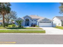 Charming single-story home with a well-manicured lawn, palm tree, and attached two-car garage at 16328 Egret Hill St, Clermont, FL 34714
