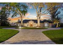 Elegant home boasts a circular driveway, arched windows and manicured lawn, with mature trees at 2844 Marquesas Ct, Windermere, FL 34786