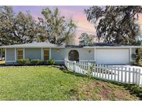 Charming single-story home featuring a well-maintained lawn and a white picket fence enhancing its curb appeal at 75 Chaney Dr, Casselberry, FL 32707
