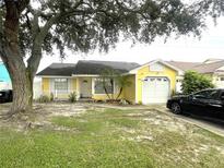 Charming yellow single-story home with a well-manicured lawn and attached one car garage at 1018 Martin Blvd, Orlando, FL 32825