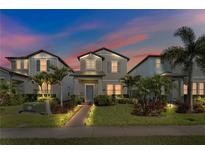Charming two-story home featuring a manicured lawn, walkway lighting, and lush tropical landscaping at 17087 Wynford Ln, Winter Garden, FL 34787
